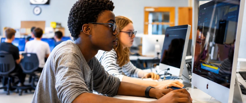 Computer science student working on programming tasks in a university computer lab