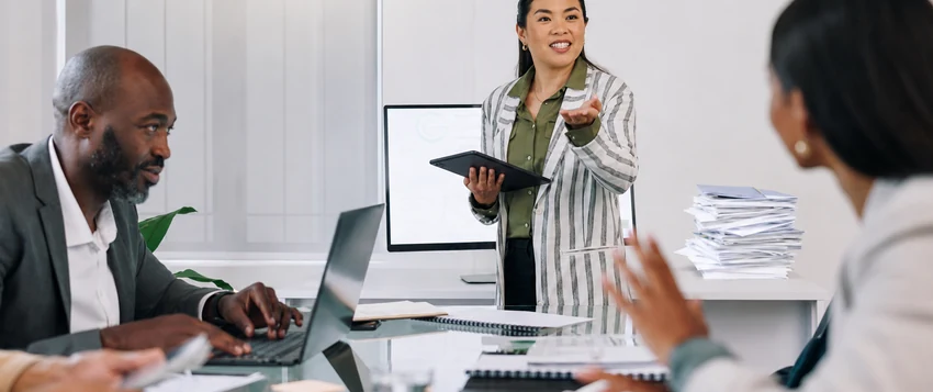 Business professional presenting to colleagues during a management meeting in a modern office