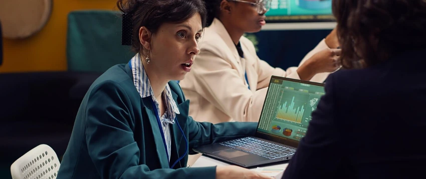 Data science professionals discussing analytics findings displayed on a laptop dashboard