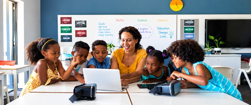Teacher guiding students using a laptop in a modern classroom