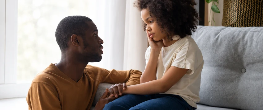 Father having a supportive conversation with his daughter at home, illustrating emotional development in childhood and family relationships