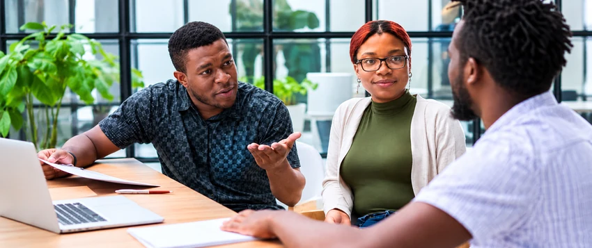 Three professionals discussing workplace behaviour in a modern office, representing Industrial Psychology