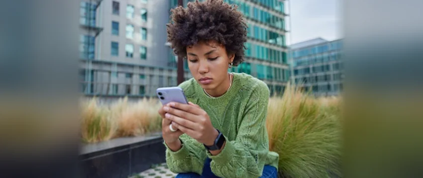 Young woman looking concerned while reading messages on her smartphone, illustrating the emotional impact of cyberbullying