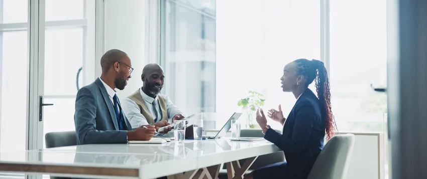 Two HR professionals interviewing a job candidate in a modern office, illustrating recruitment and selection practices